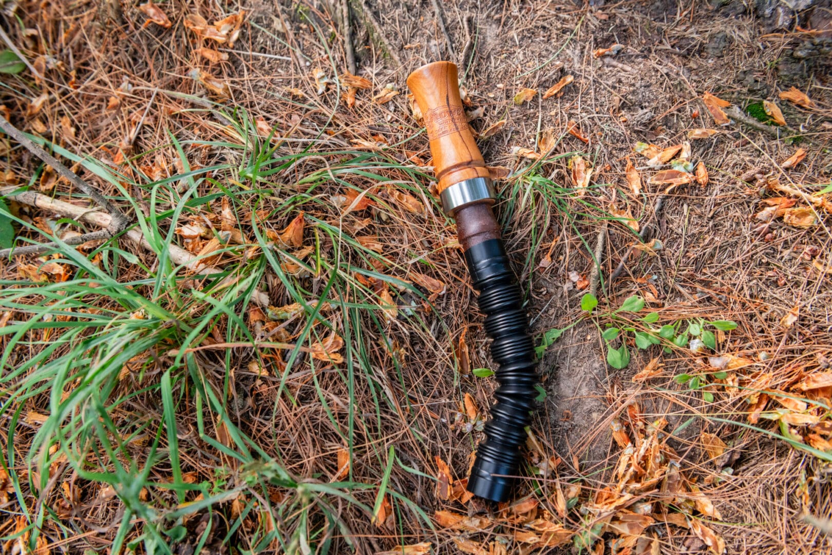 A broken flashlight laying on the ground in the grass.
