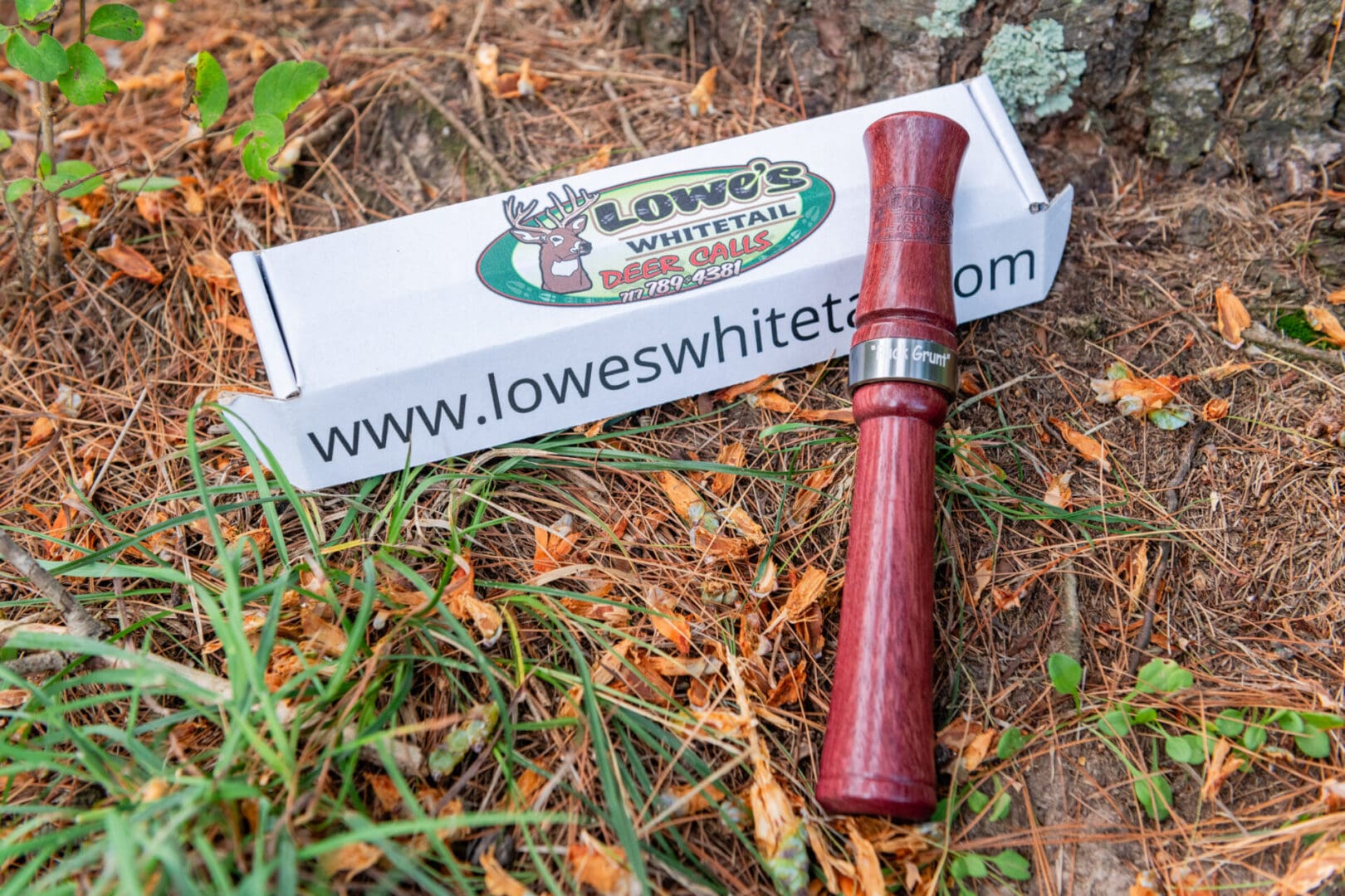 A red pipe laying in the grass next to a box of matches.