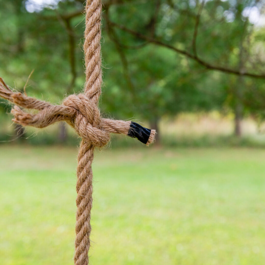 A rope tied to a wooden pole with a pencil stuck in it.
