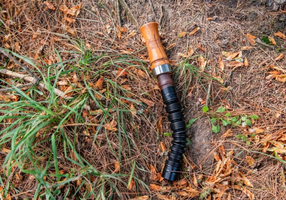 A broken flashlight laying on the ground in the grass.